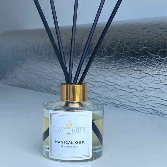 Magical Oud Reed Diffuser which is used to scent a room. Scented room diffuser in a glass bottle with gold lid and black reed sticks